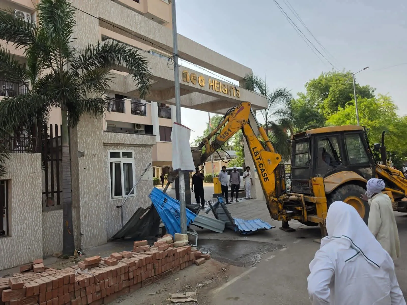 Neo Heights अपार्टमेंट के मुख्य गेट पर चला बुलडोजर, सड़क पर अवैध कब्जा हटाया।